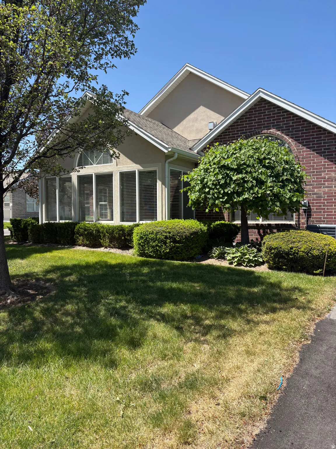 Brick and stucco exterior featuring multiple gables and a sunroom with arched transom window