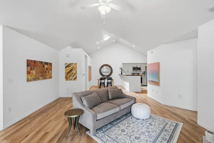 Expansive living area featuring vaulted ceilings, wood-finish flooring, and recessed lighting