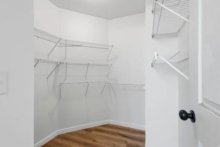 Walk-in closet featuring wire shelving, white walls, and wood-finish flooring