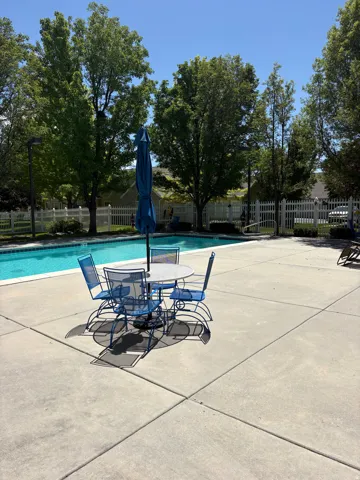 Expansive concrete patio surrounding a swimming pool with a white coping border
