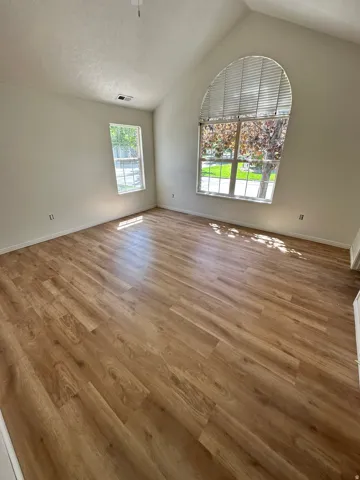 Vaulted ceiling room featuring wood-finish flooring