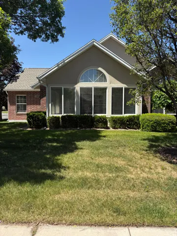 Gable-front stucco facade featuring a prominent arched transom window