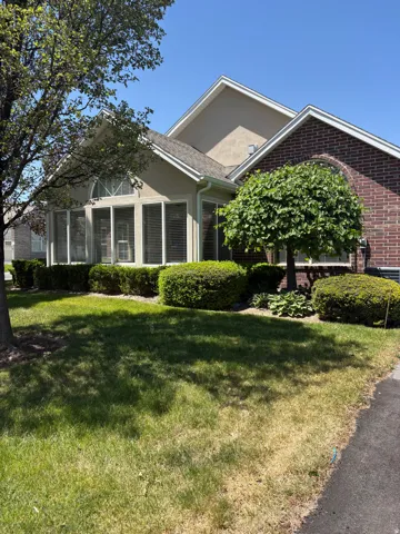 Brick and stucco exterior featuring multiple gables and a sunroom with arched transom window