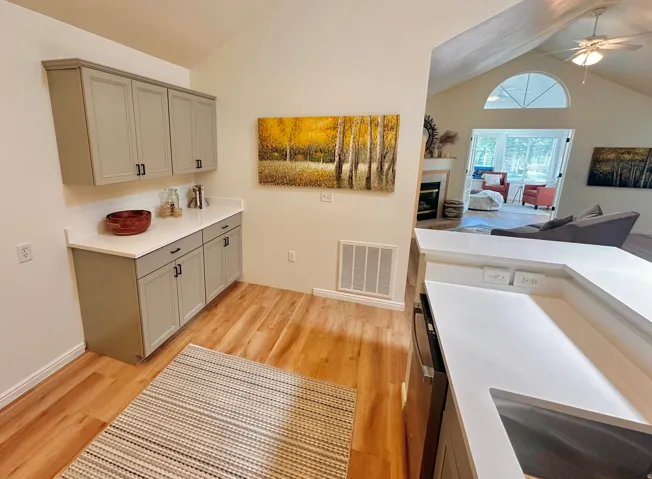 Kitchenette featuring light gray cabinetry with dark hardware, white countertops, and wood-finish flooring