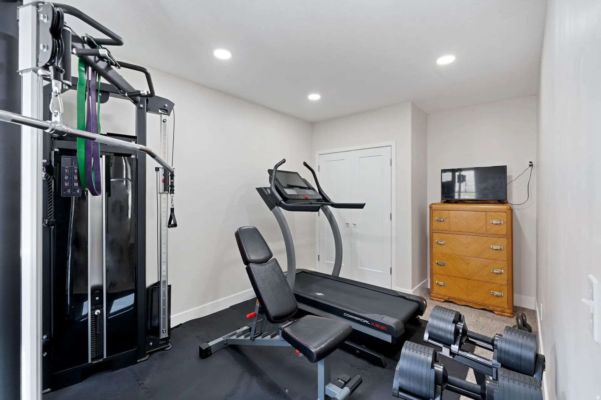Basement dedicated fitness space or bedroom featuring a black rubber flooring system and recessed ceiling lighting