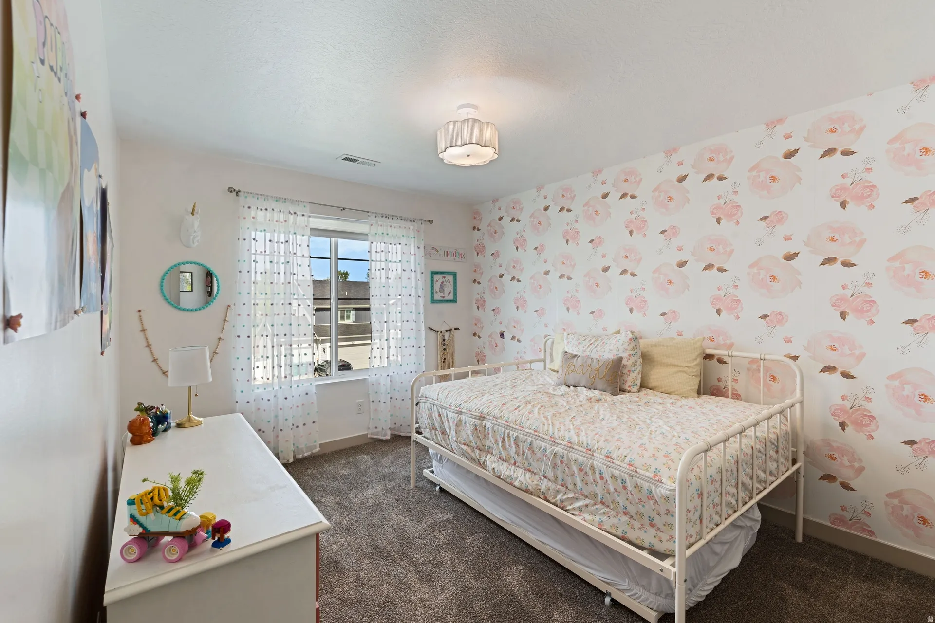 Room featuring a single window, a floral accent wall, and a textured carpeted floor