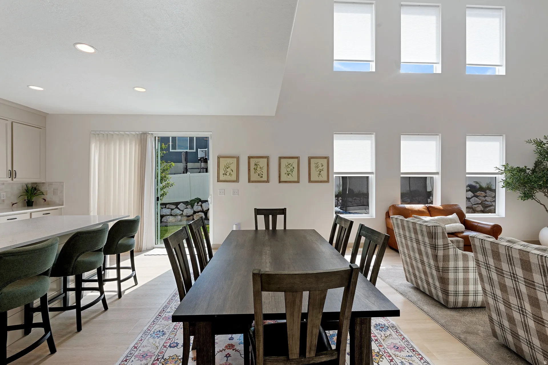 Open-concept living area featuring high ceilings with recessed lighting, an expansive kitchen island with bar seating, and light wood-finish flooring