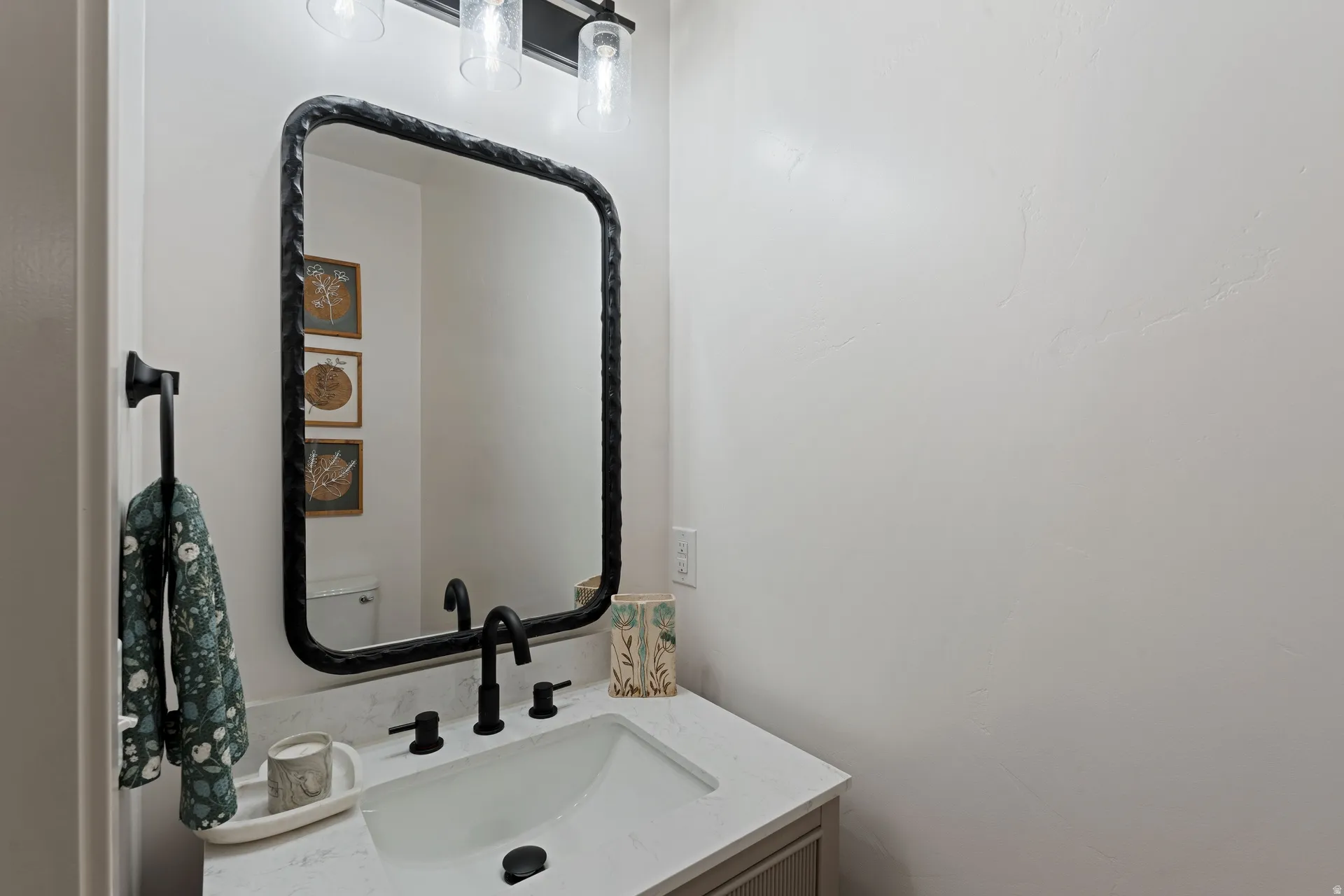 Modern vanity featuring a rectangular undermount sink, light-toned countertop, and matte black widespread faucet