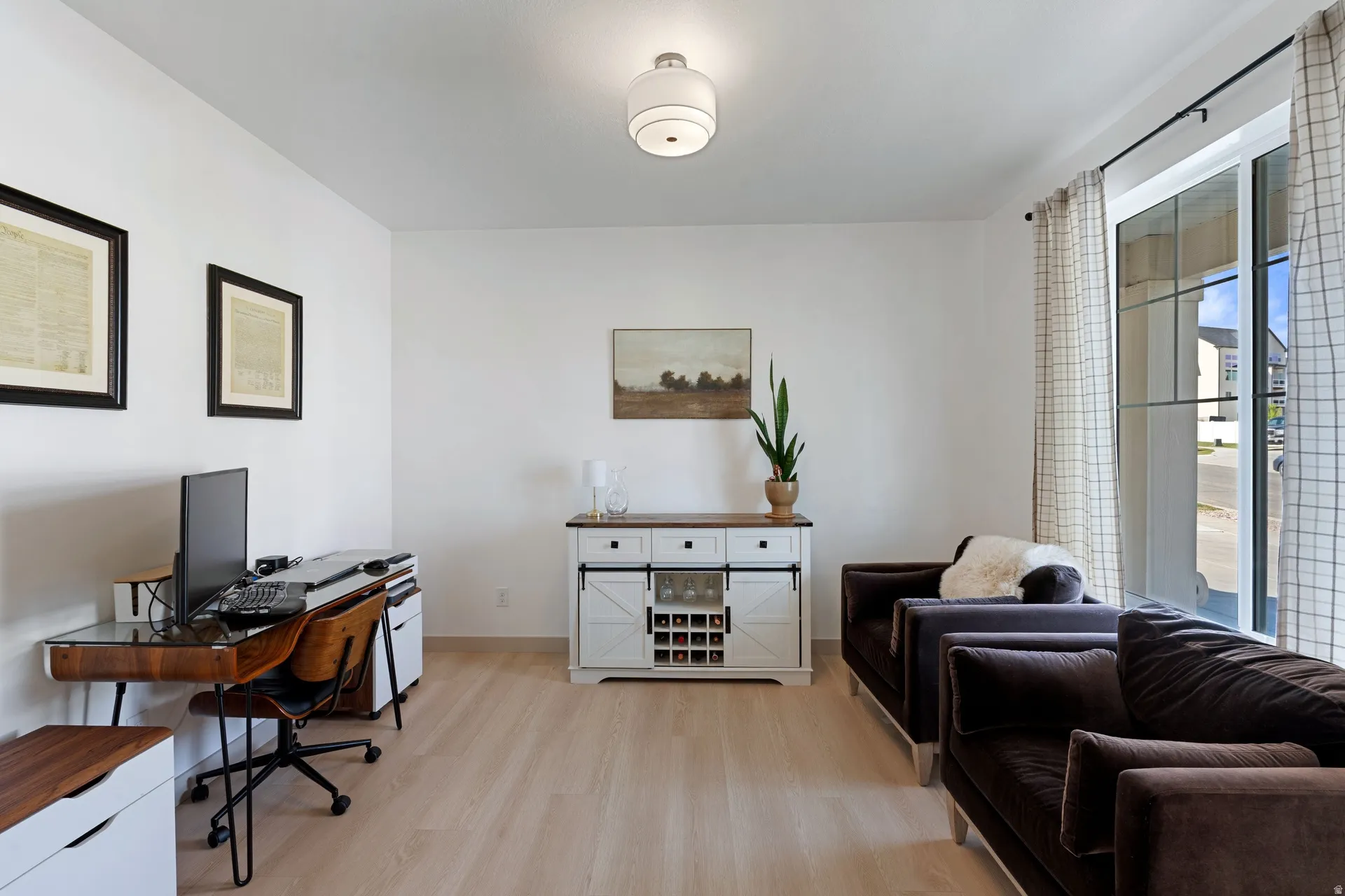 Bright living space featuring light wood-finish flooring, white walls, and a contemporary ceiling light fixture