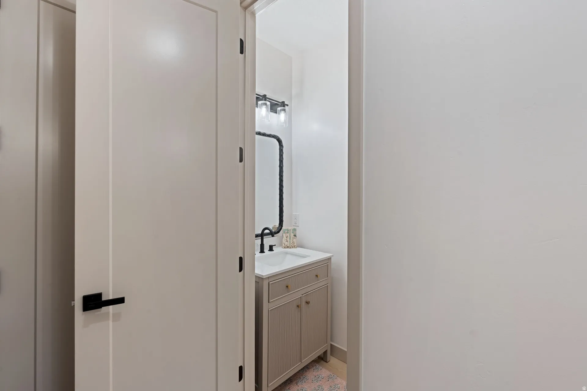 Powder room featuring a single vanity with a white countertop, undermount sink, and matte black faucet