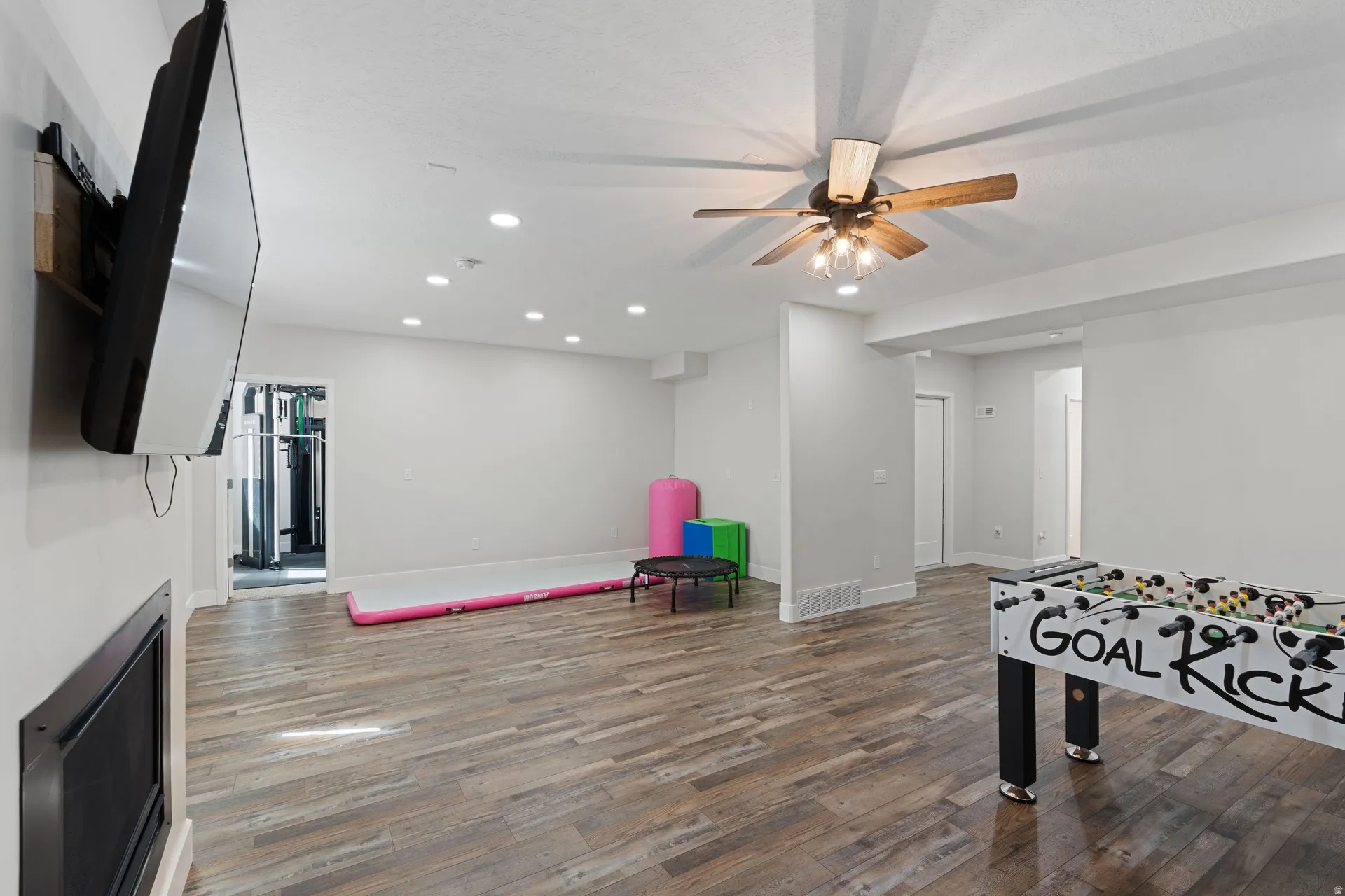 Basement spacious entertainment area featuring wood-finish flooring, recessed lighting, and a ceiling fan with integrated lighting
