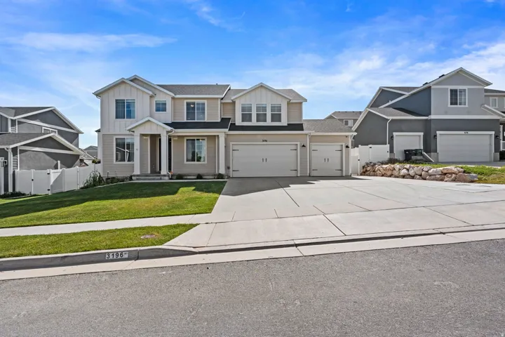 Contemporary two-story residence featuring a neutral exterior, a covered front entry with columns, and a four-car garage