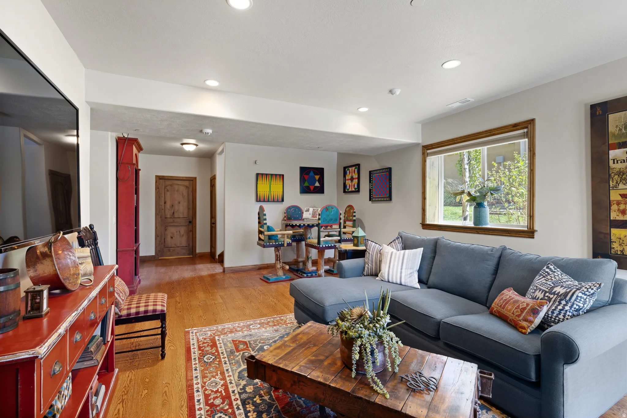 Open-concept living space featuring wood-finish flooring, recessed lighting, and a window with wood trim