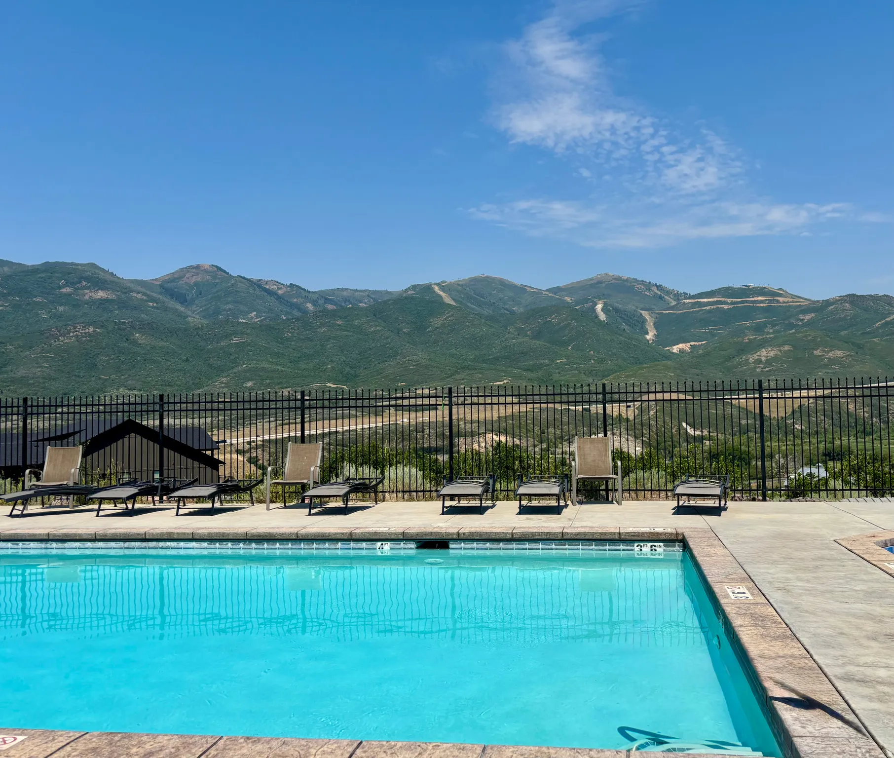Outdoor swimming pool with a concrete surround and mountain backdrop