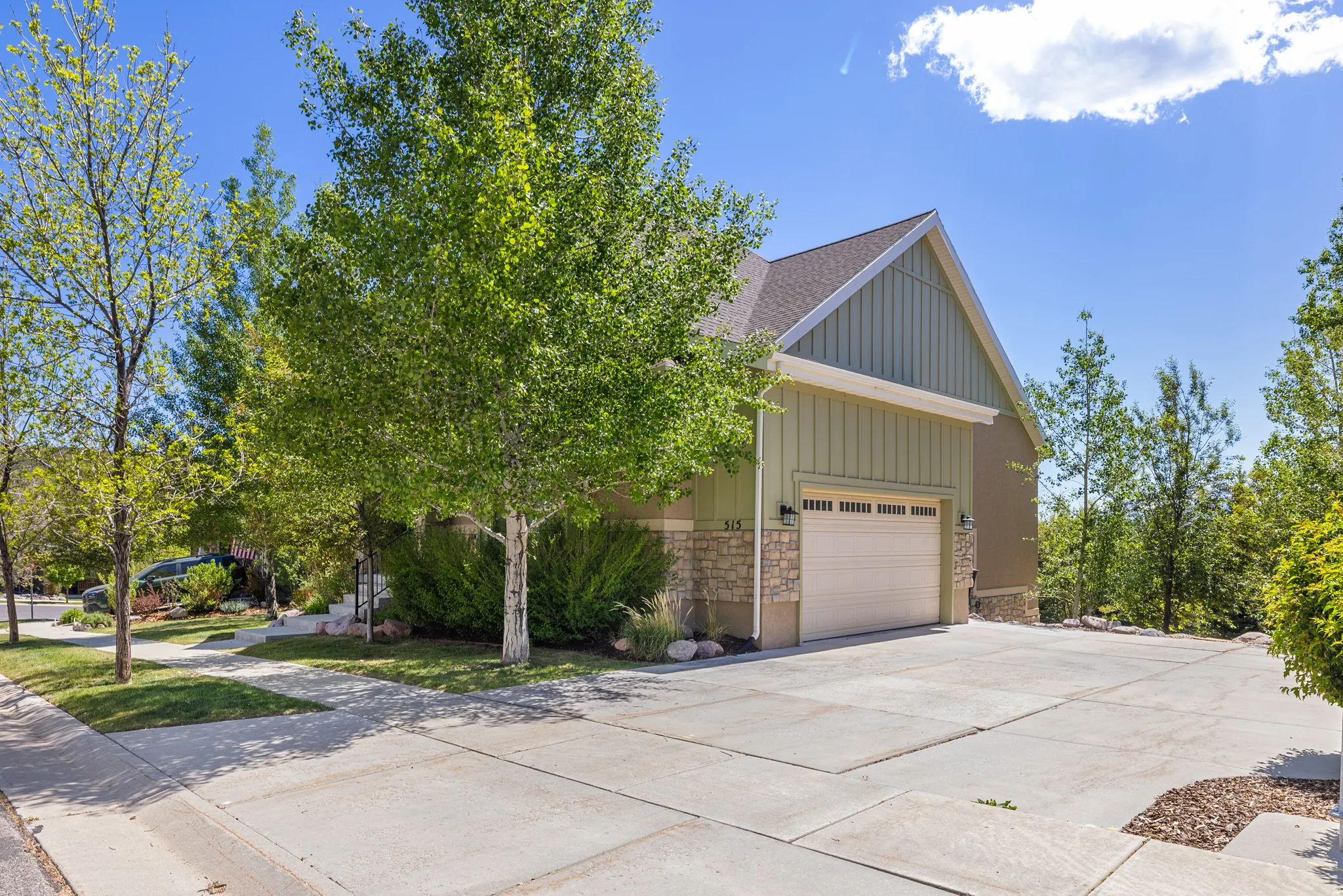 Exterior featuring vertical board-and-batten siding, stone veneer accents, a pitched roof, and an attached two-car garage