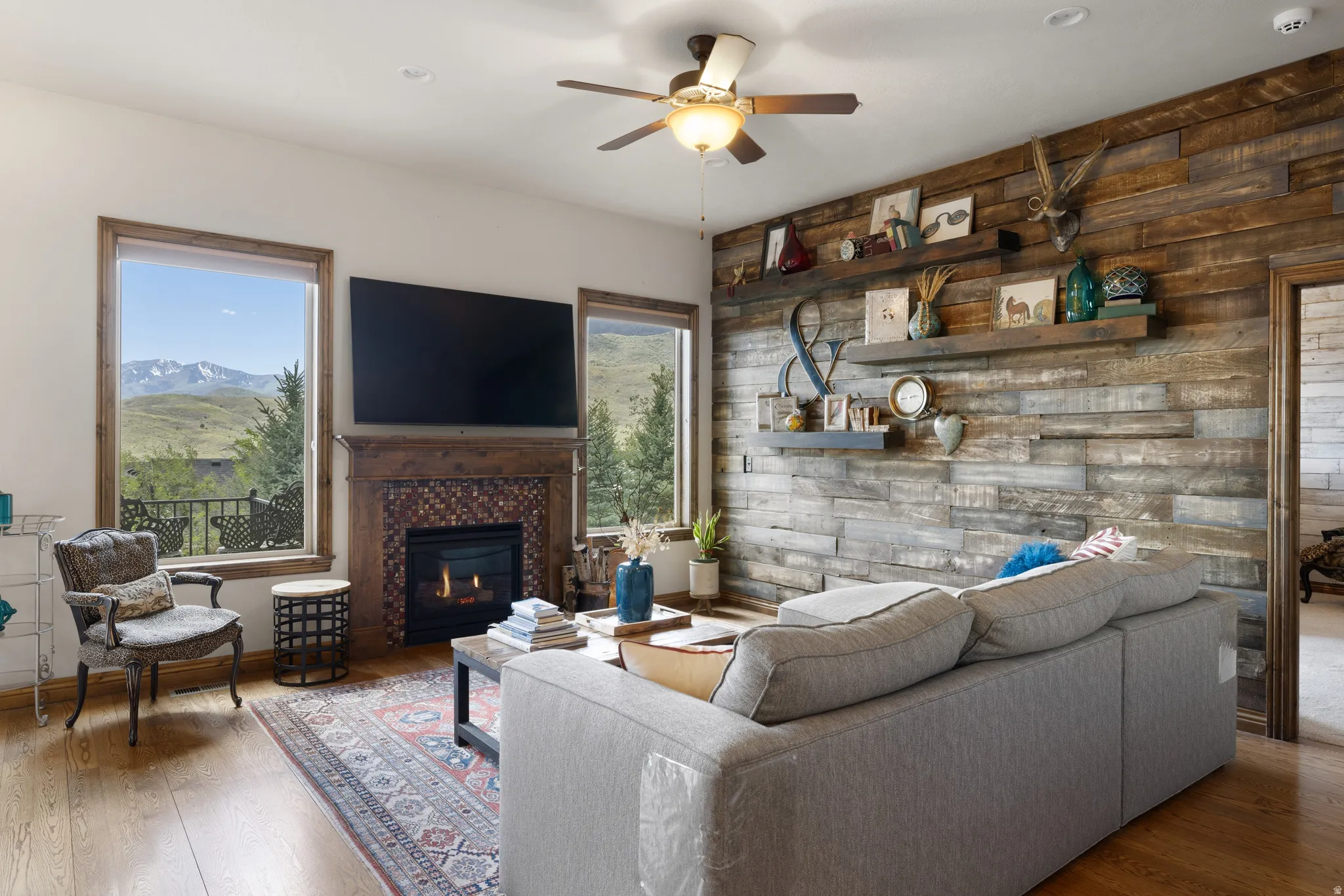 Living area featuring wood-finish flooring, a wood plank accent wall with built-in shelving, and a fireplace with a decorative tile surround and mantel