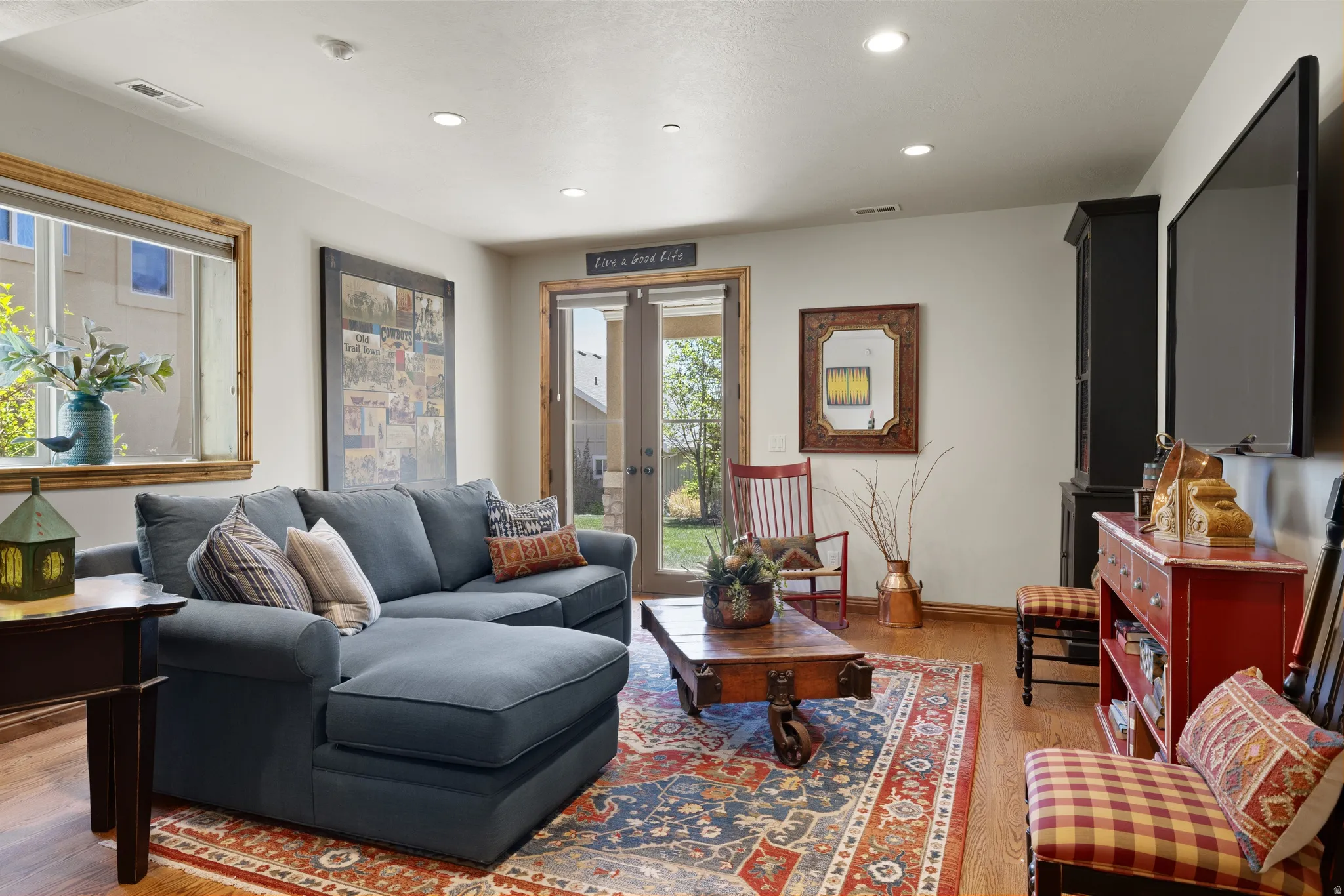 Living space featuring wood-finish flooring, recessed lighting, and a large window with wood trim