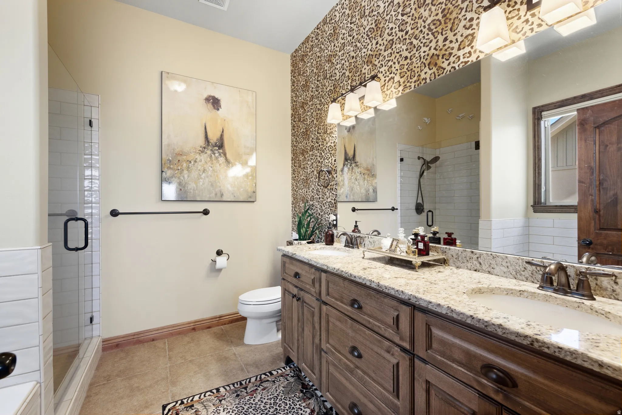 Dual vanity with granite countertops and integrated sinks, complemented by a large mirror and overhead multi-bulb lighting