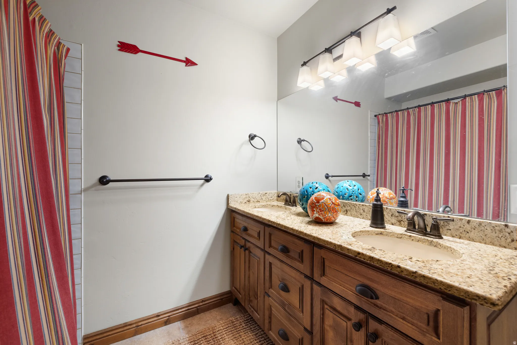 Double vanity featuring granite countertops with integrated sinks, wood-finish cabinetry, and oil-rubbed bronze fixtures