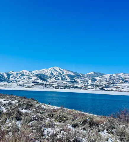 Expansive water body with snow-covered mountains in the background, featuring distinct ski trails