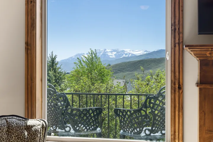 Balcony overlooking a mountainous landscape, featuring a black metal railing and a wood-trimmed window
