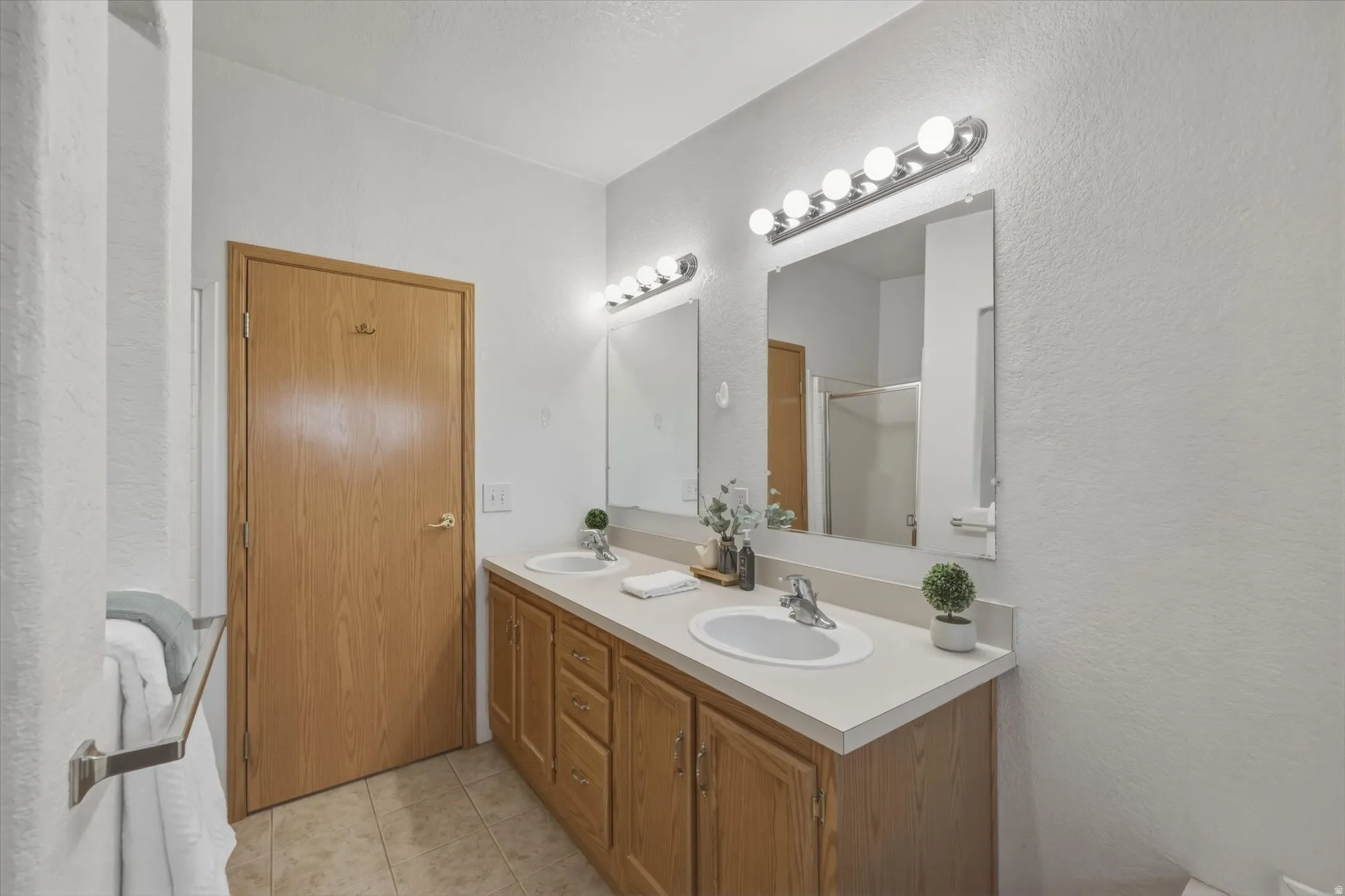 Double vanity featuring two sinks with chrome faucets, individual mirrors, and overhead bar lighting