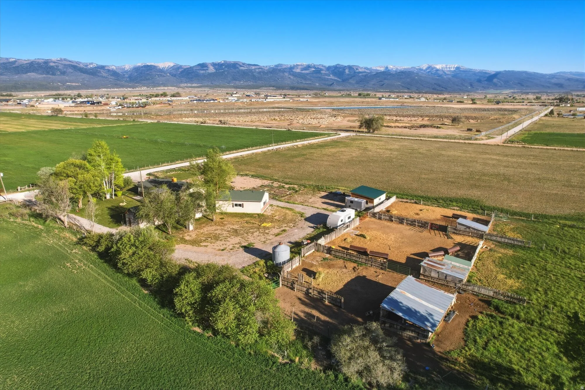 Expansive property featuring multiple outbuildings, fenced enclosures, and a large metal-roofed structure