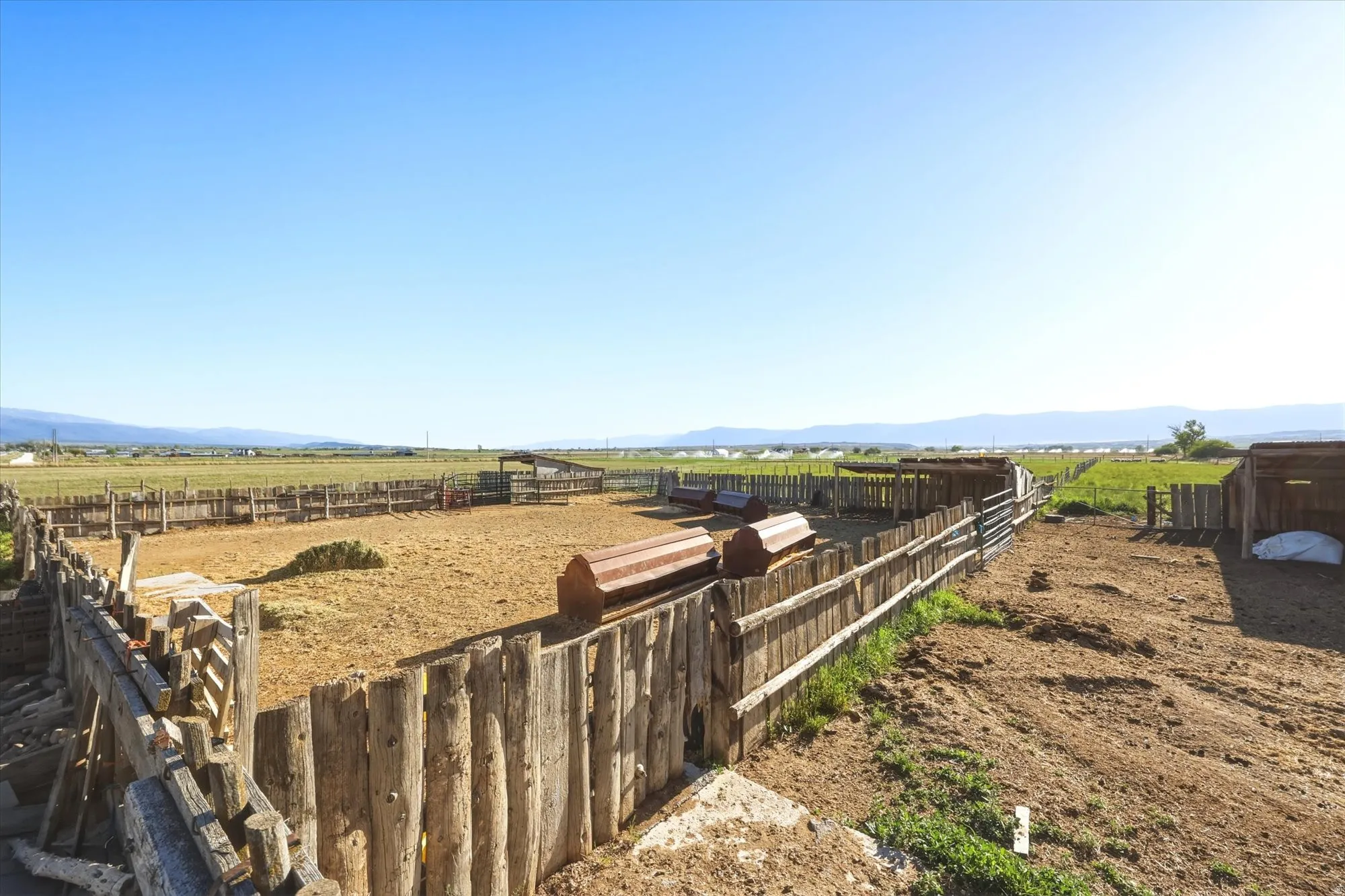 Expansive property featuring multiple fenced corrals, open fields, and distant mountain ranges