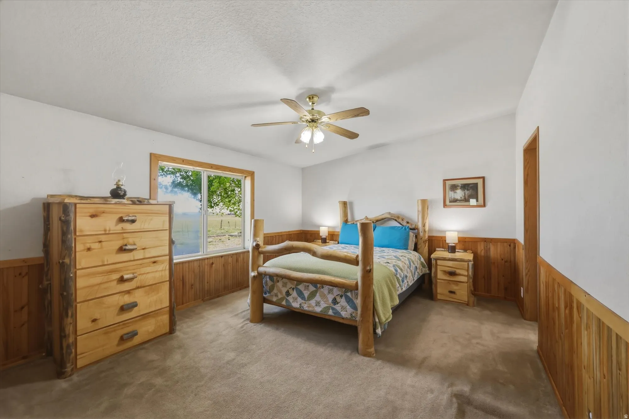 Carpeted room with a ceiling fan light fixture, white walls, and wood-paneled wainscoting