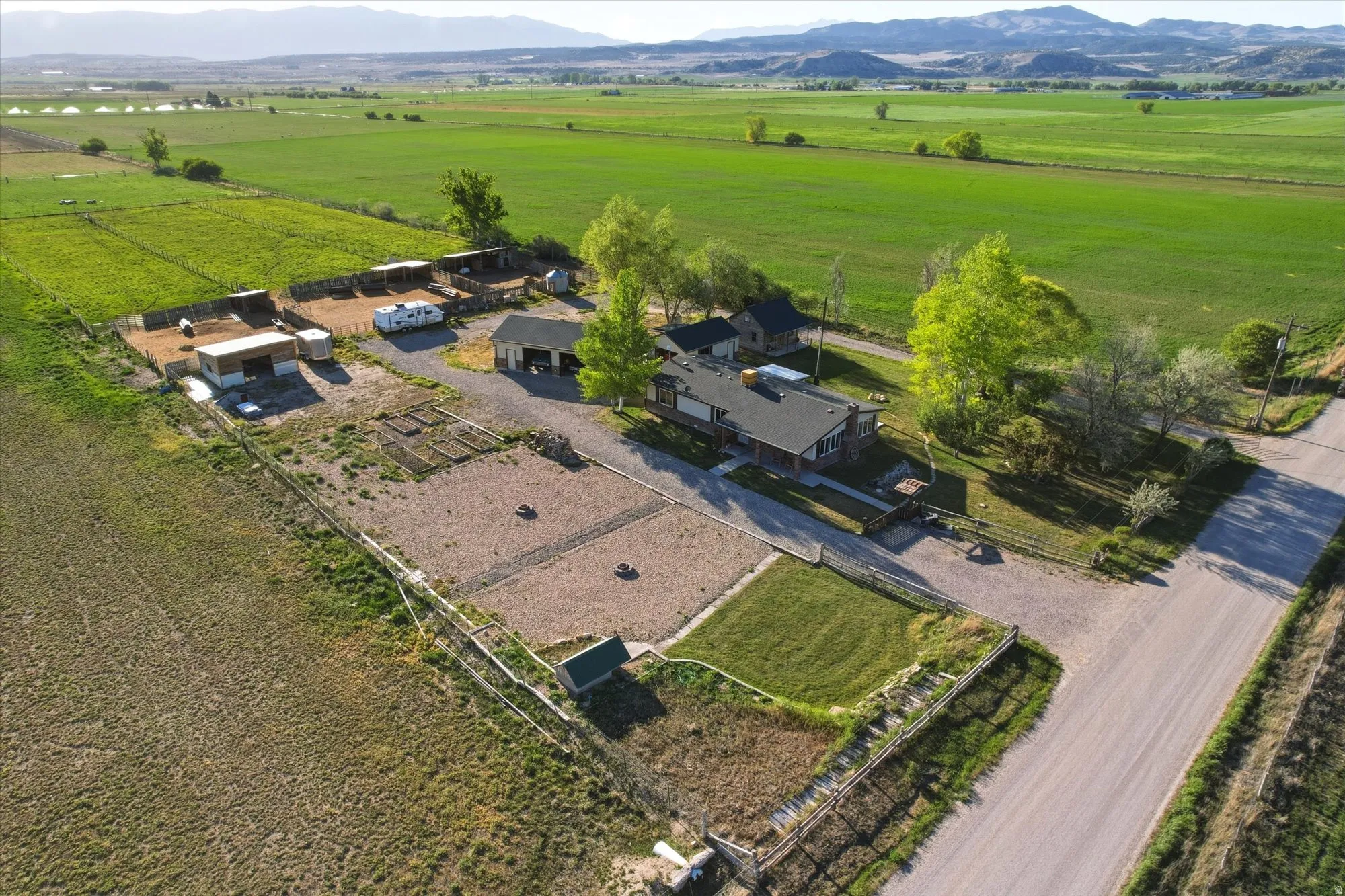 Expansive property featuring a residence with a dark roof, multiple outbuildings, and fenced areas