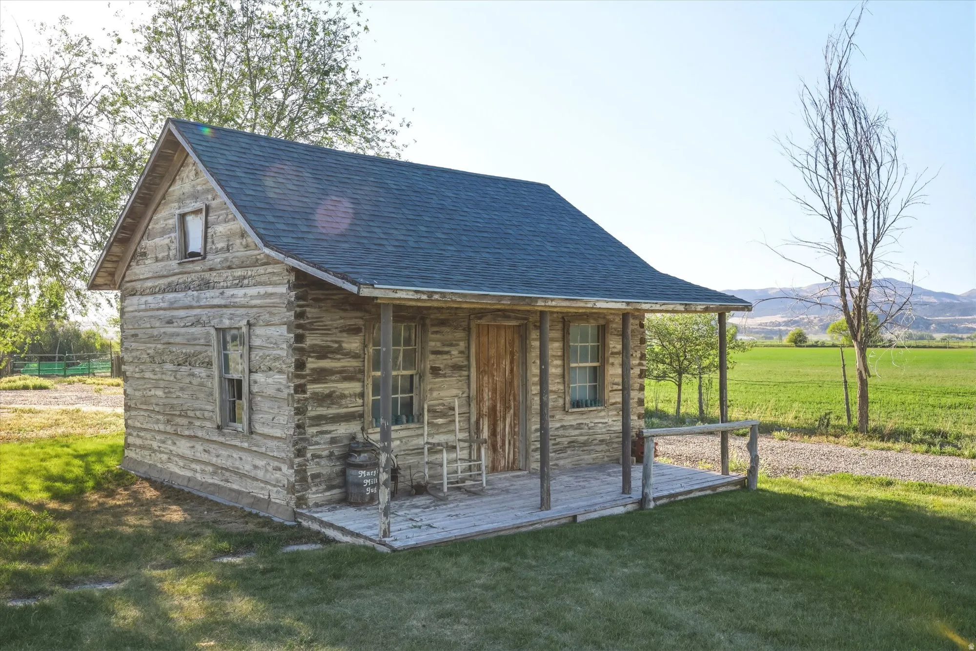 Rustic log cabin with a dark shingle roof and a covered front porch featuring a wood railing