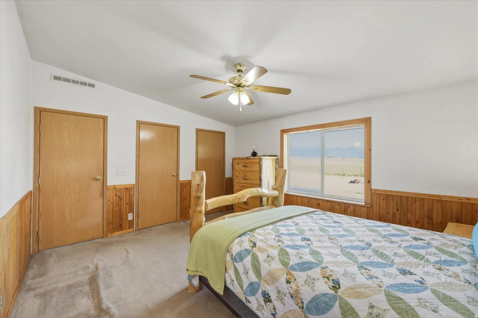 Carpeted room featuring wood paneling along the lower walls and a large window with a wood frame