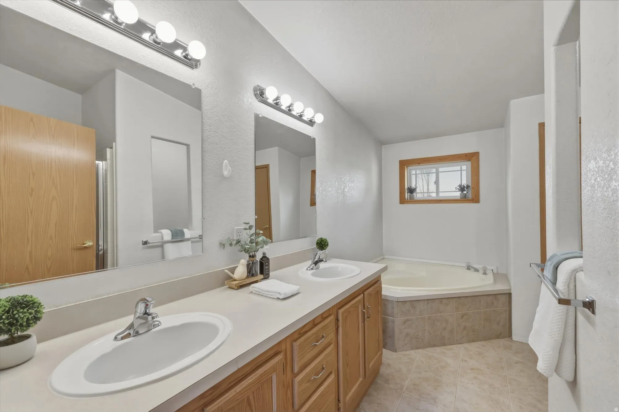 Bathroom featuring a dual vanity with light wood cabinetry, two oval undermount sinks, and chrome faucets