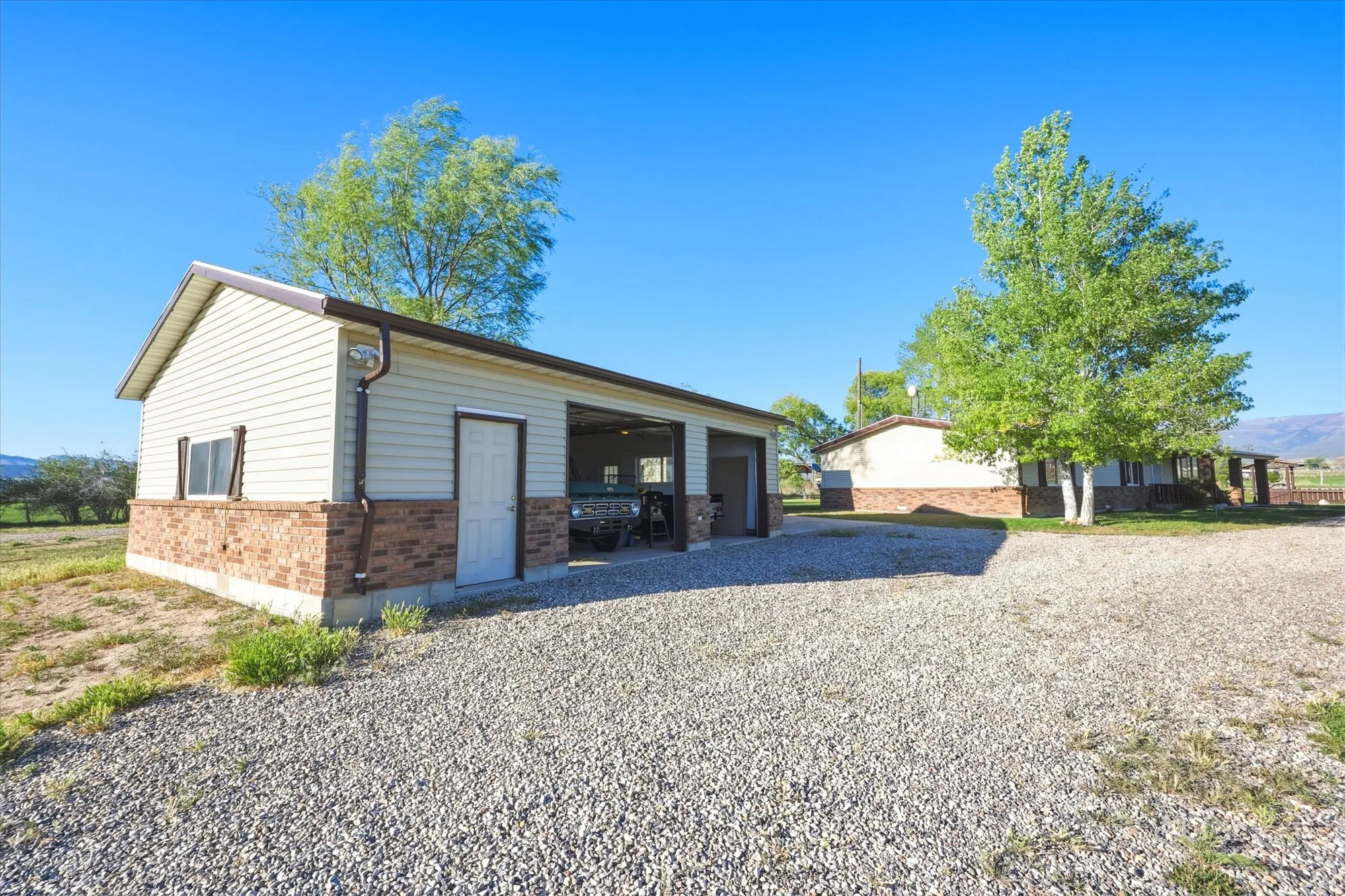 Detached two-bay garage with light-colored siding and a brick-finish base