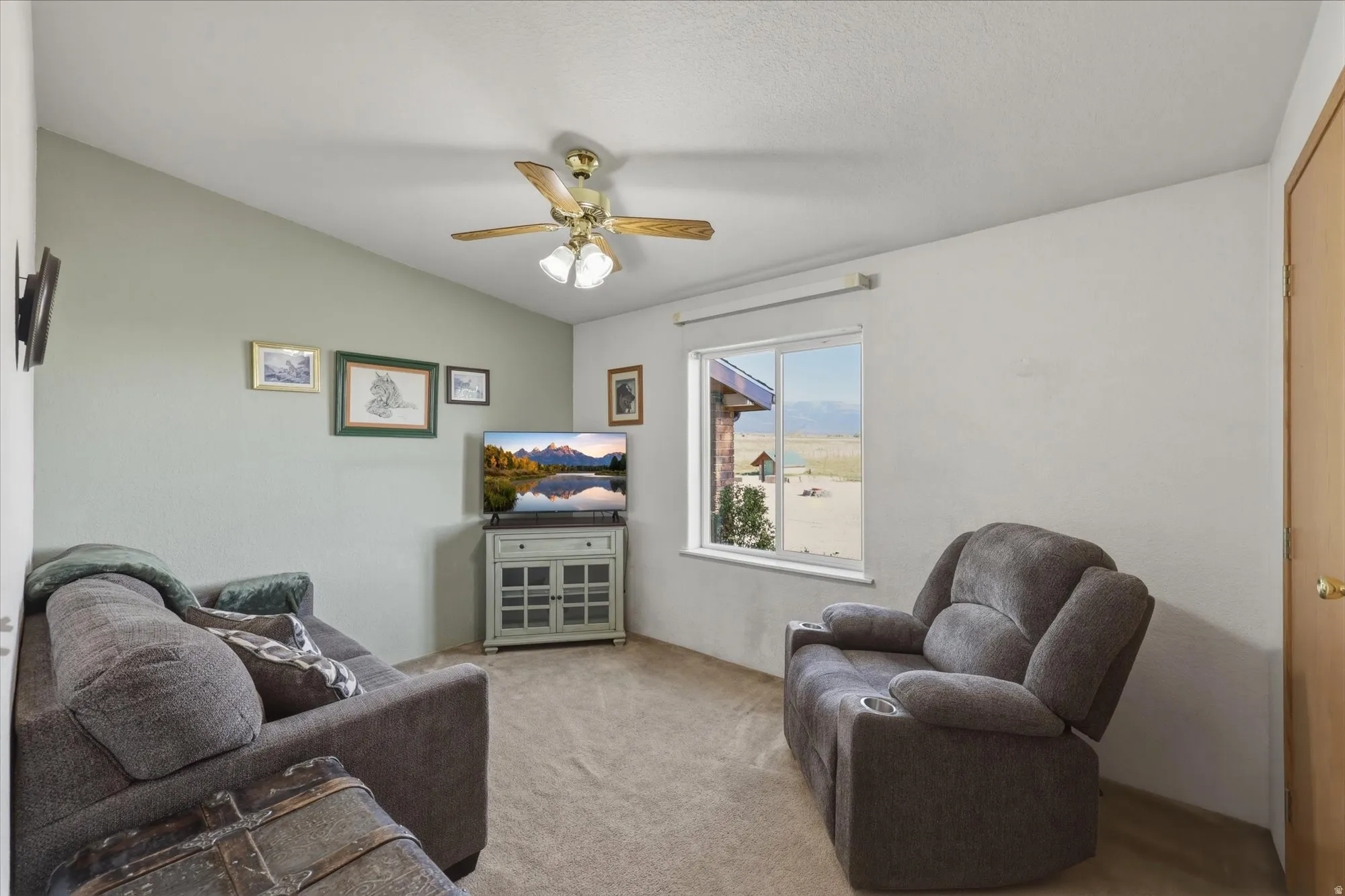 Carpeted living area featuring a vaulted ceiling with a ceiling fan