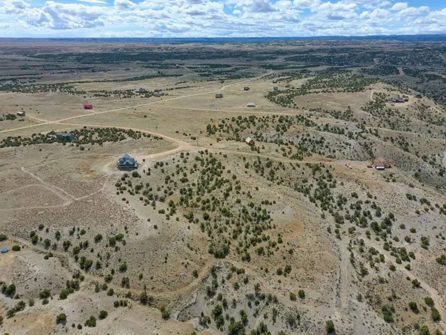 Expansive elevated acreage featuring a custom-built residence with a distinctive turret and multiple surrounding structures