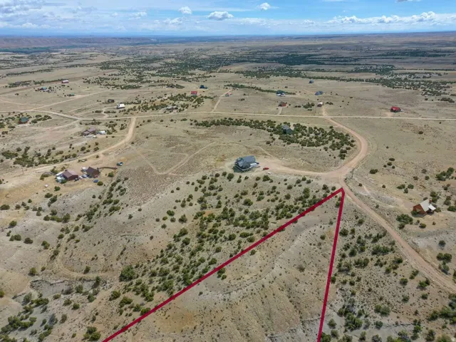 Expansive undeveloped land parcel featuring natural desert flora, a gently sloping terrain, and a visible property boundary