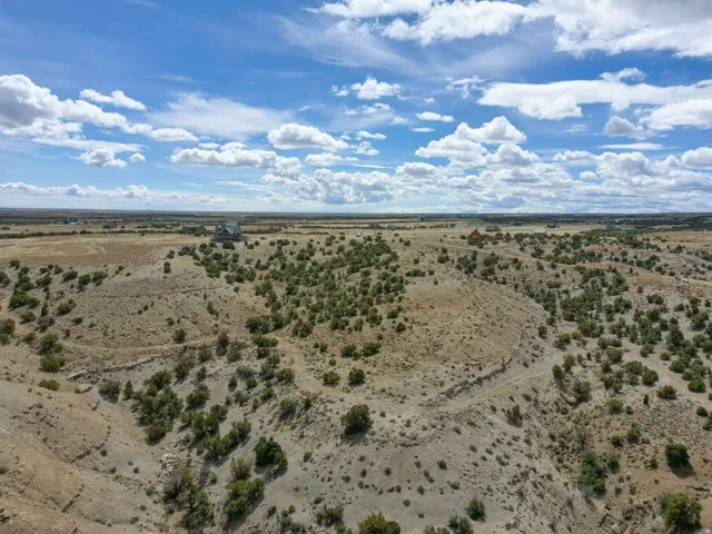 Expansive desert landscape featuring rolling terrain and scattered green vegetation