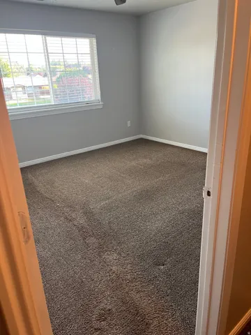 Carpeted interior room with neutral gray walls and white trim