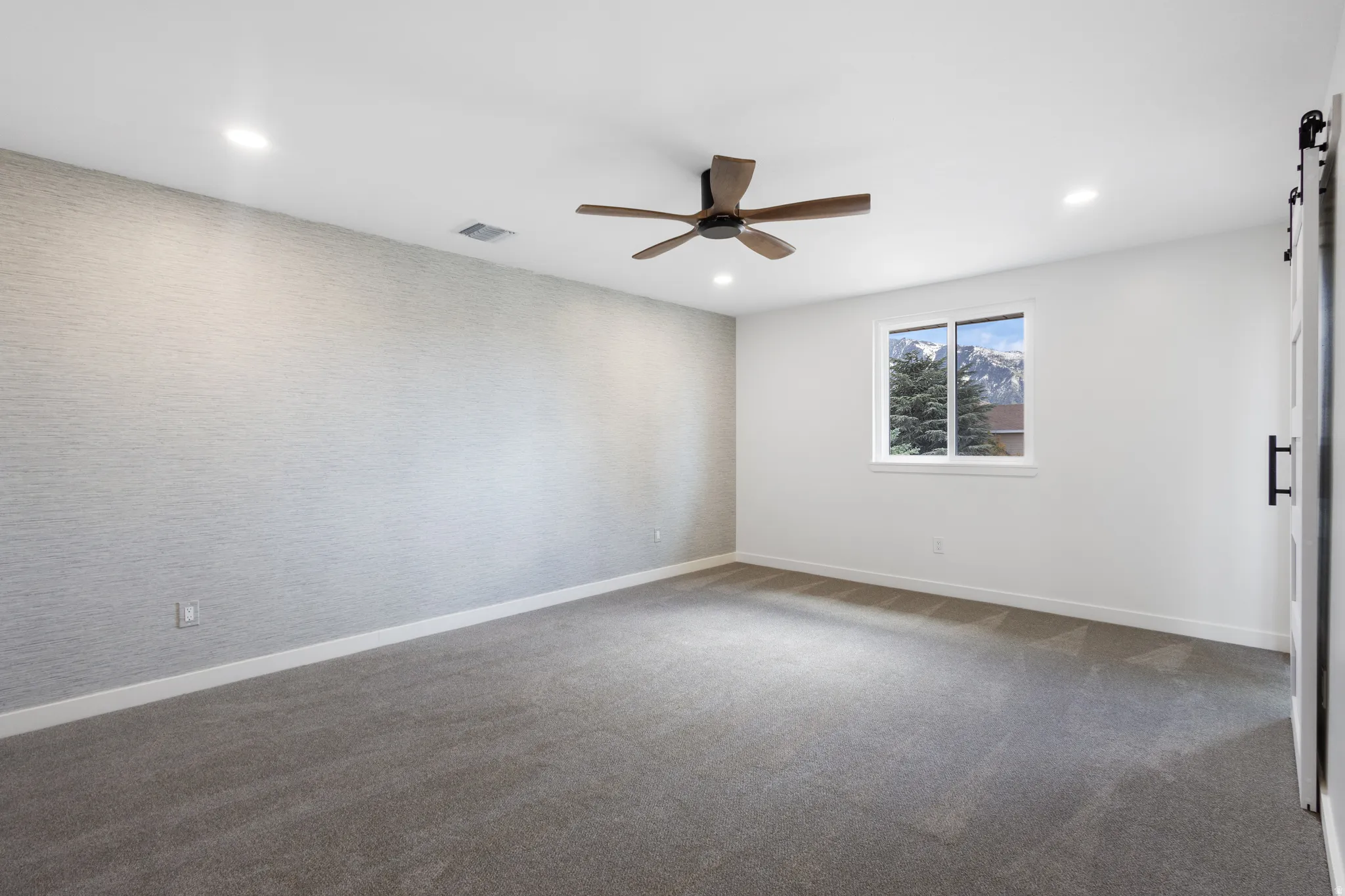 Spacious room featuring neutral carpeting and a textured accent wall
