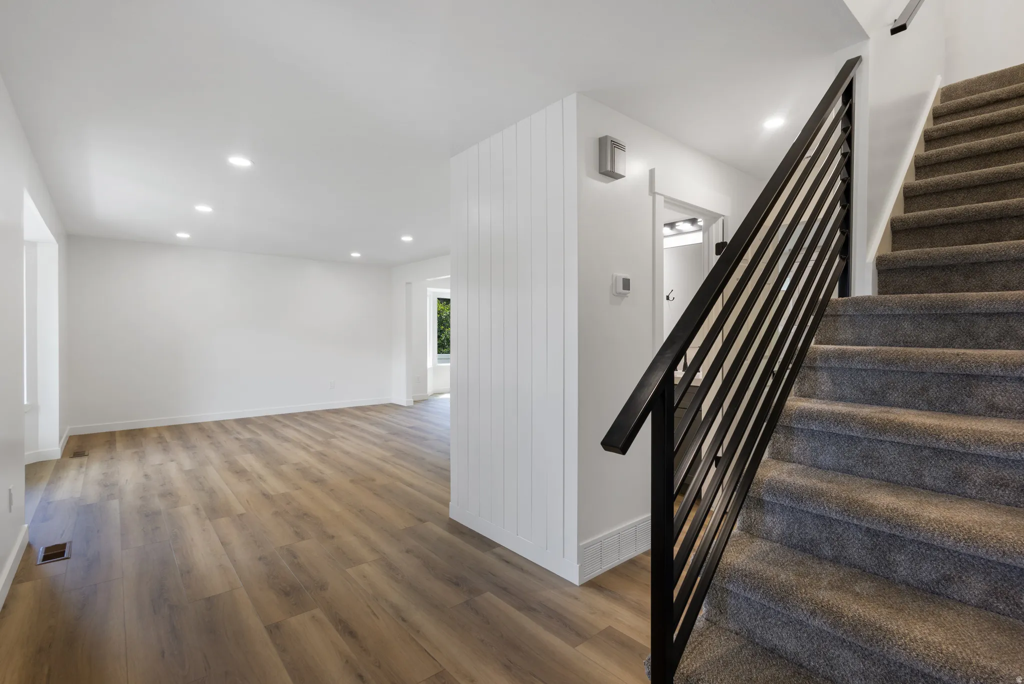 Open-concept living space featuring wood-finish flooring, recessed lighting, and white walls