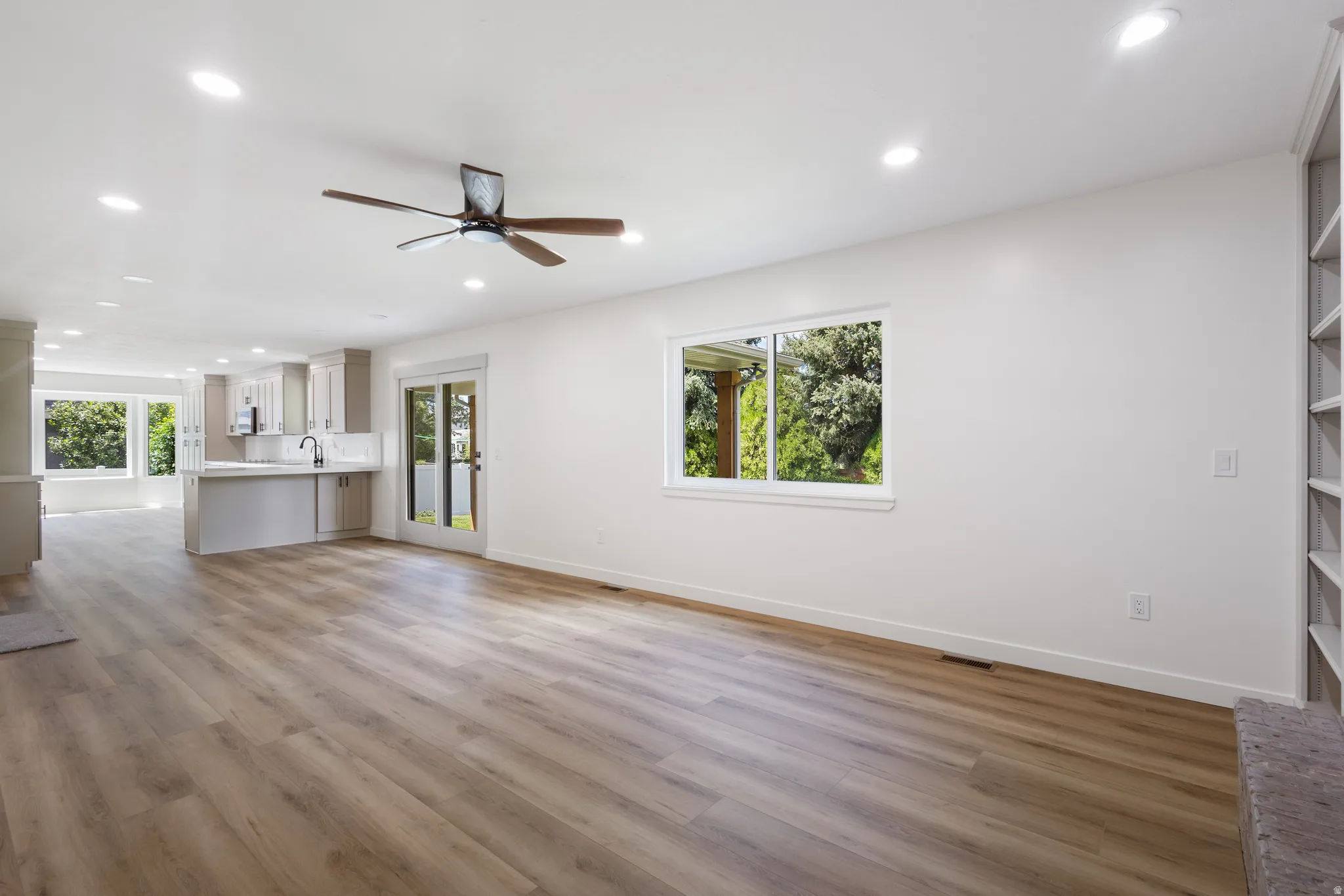 Open-concept living area featuring wood-finish flooring, recessed lighting, and a ceiling fan