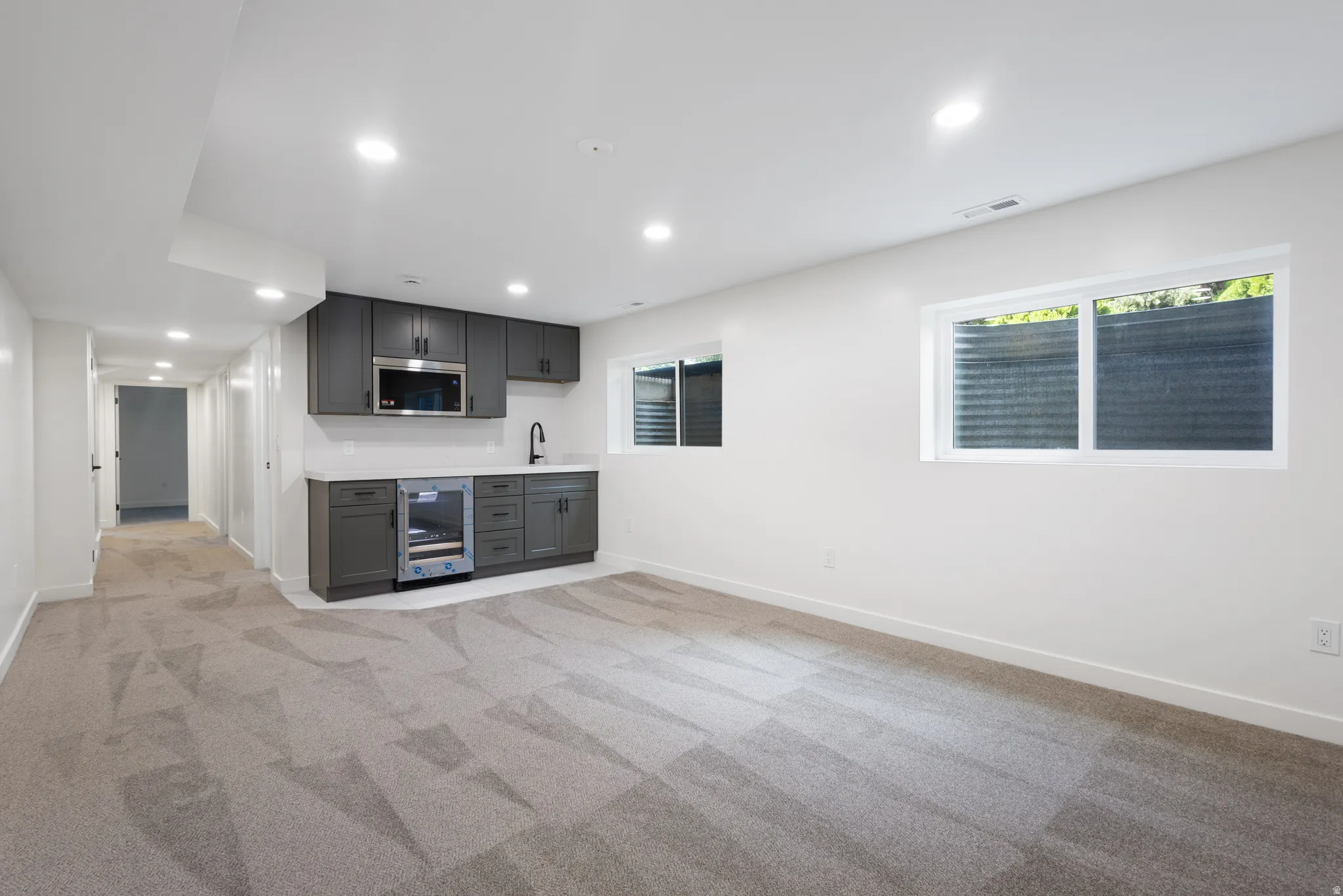 Spacious interior room featuring a built-in wet bar with dark cabinetry, integrated microwave, and beverage refrigerator