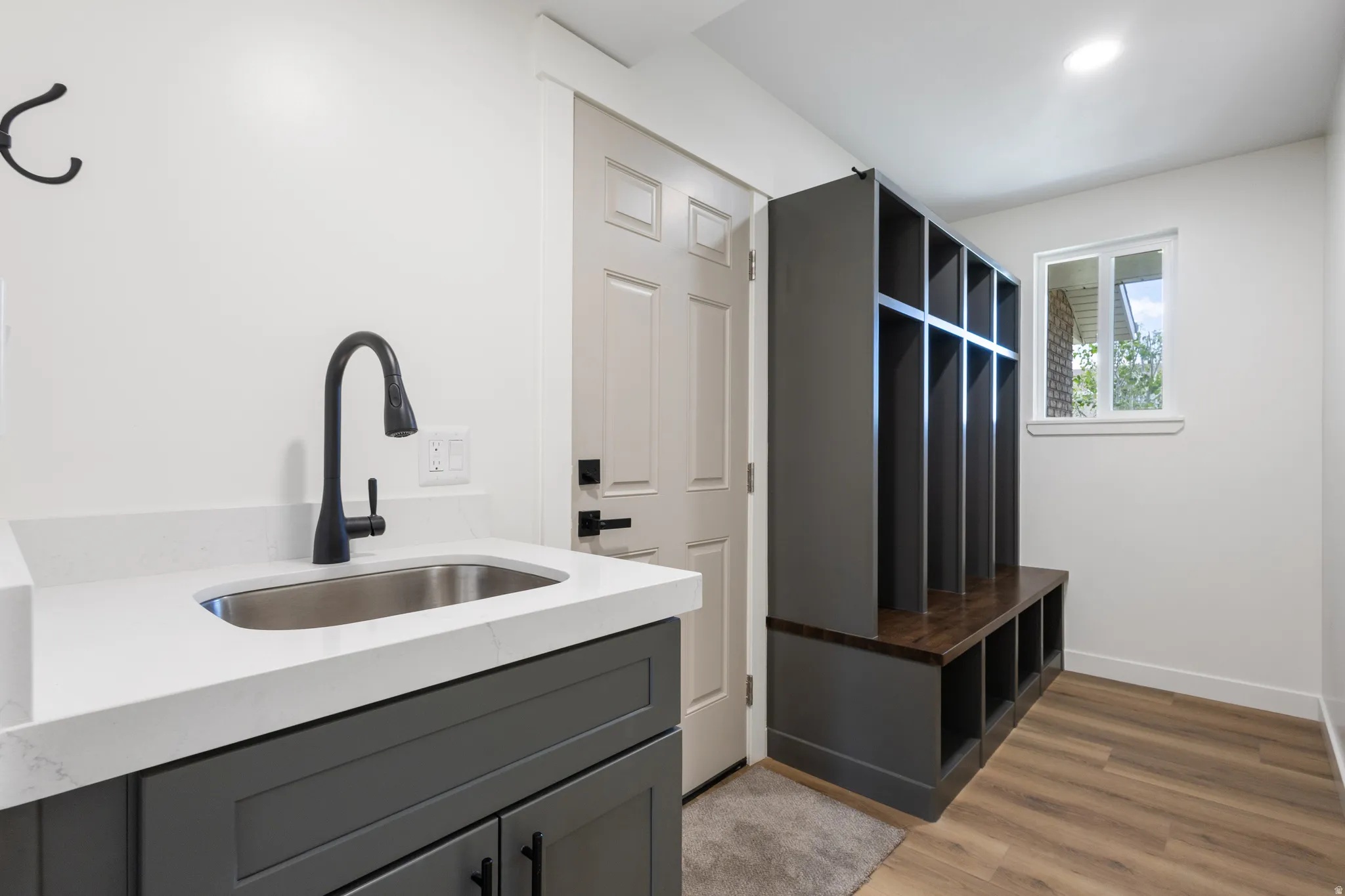 Utility space featuring a built-in sink with matte black hardware, white countertop, and dark gray cabinetry
