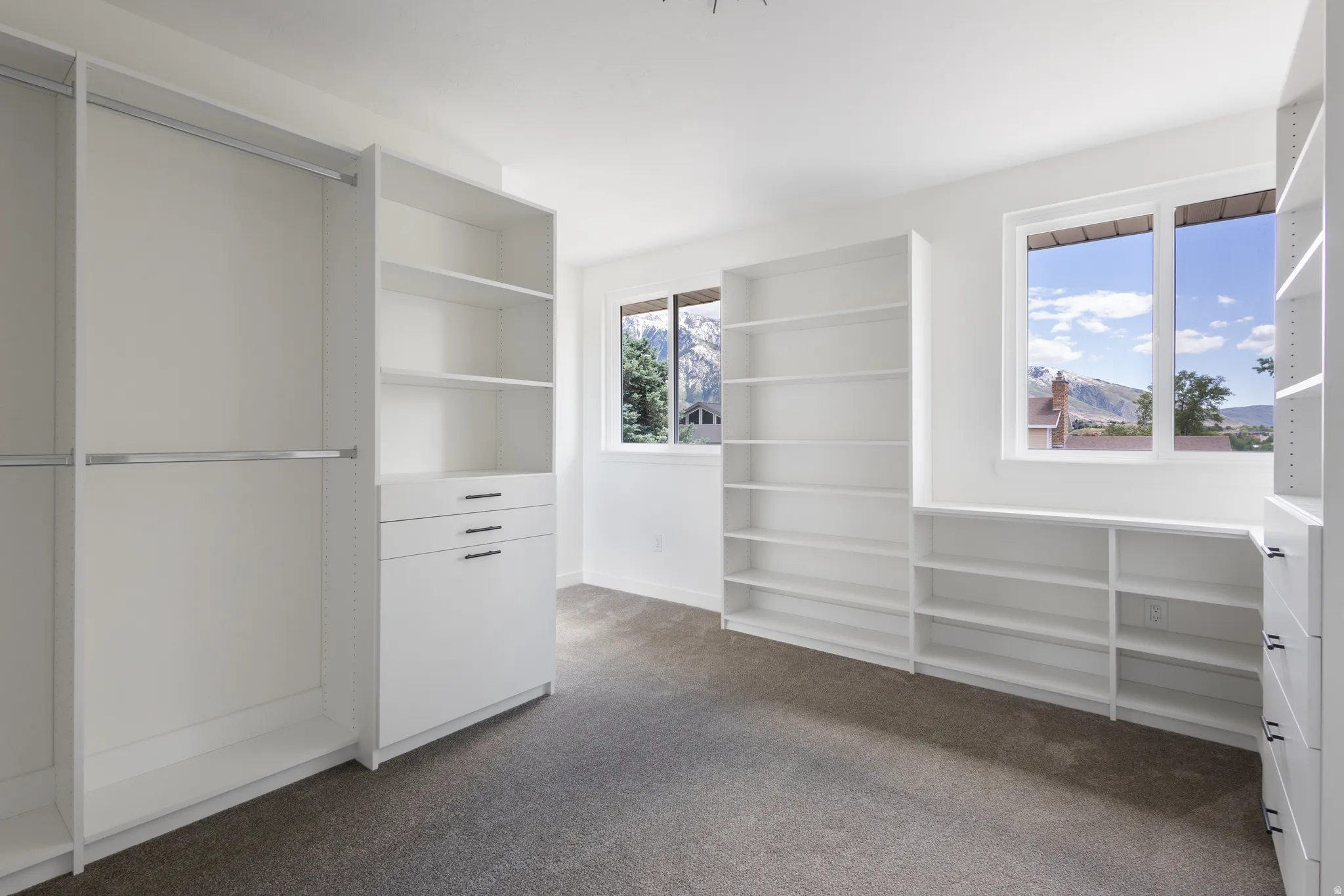 Spacious walk-in closet featuring extensive built-in shelving, hanging rods, and integrated drawers