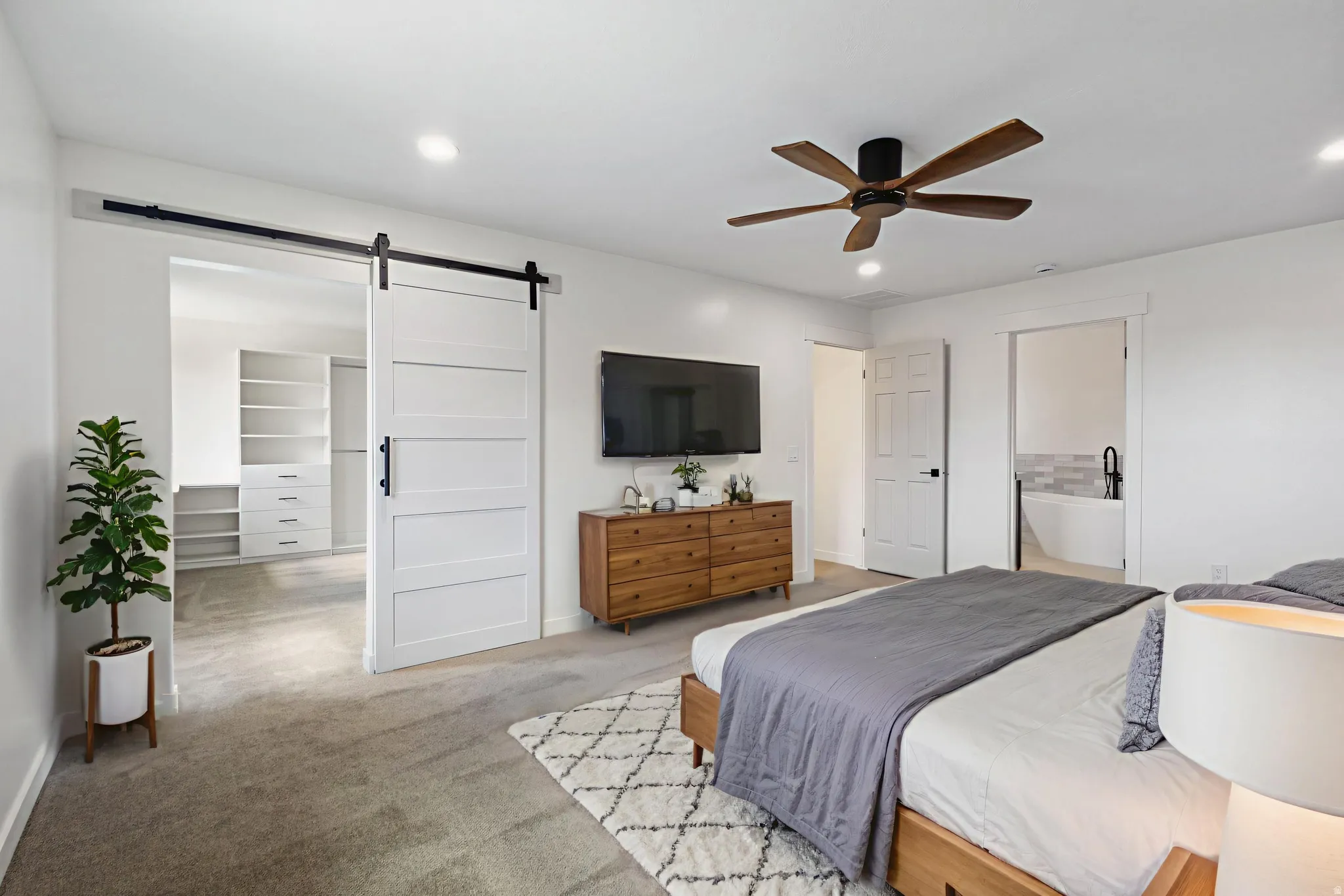 Carpeted room featuring a modern ceiling fan with wood-finish blades, recessed lighting, and white trim