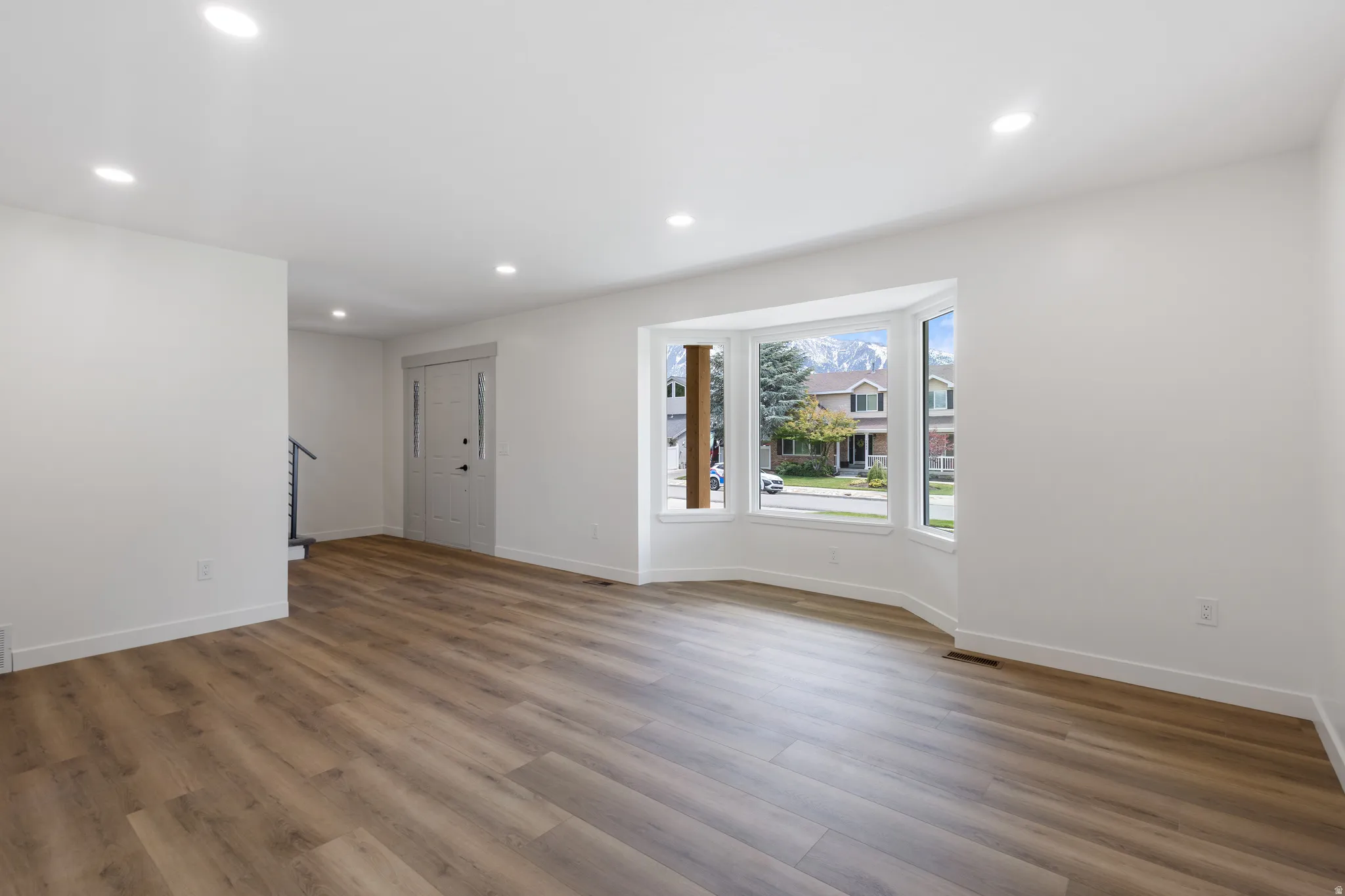 Spacious interior featuring wood-finish flooring, recessed lighting, and a bay window