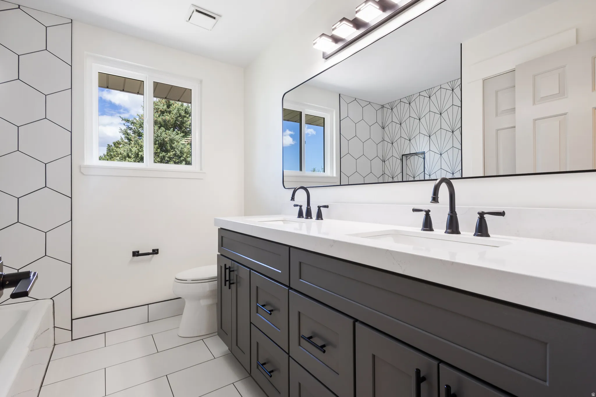 Dual vanity with white countertop, matte black fixtures, and integrated sinks