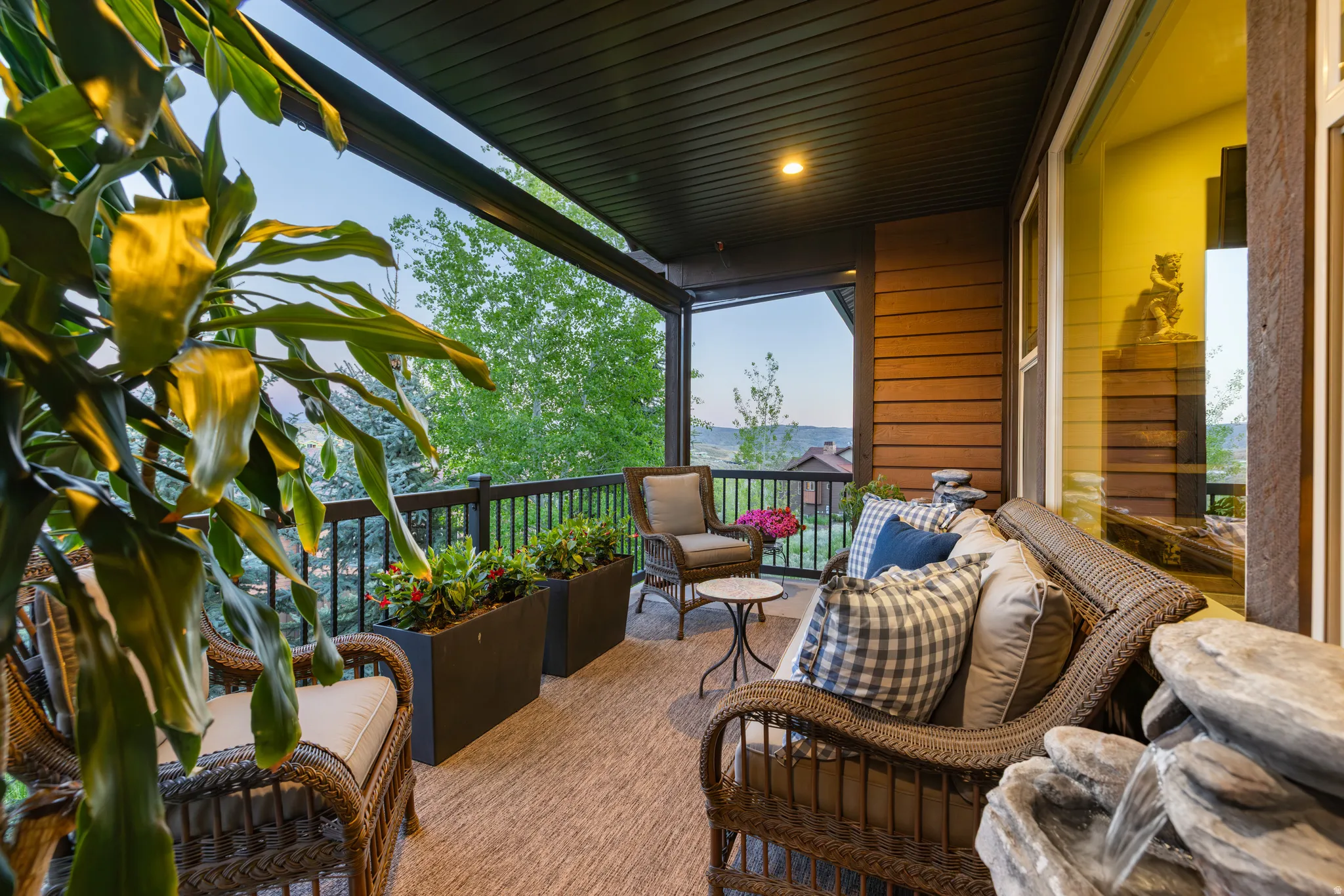 Covered outdoor patio featuring wood-finish siding, a dark soffit ceiling, and a black wrought-iron railing