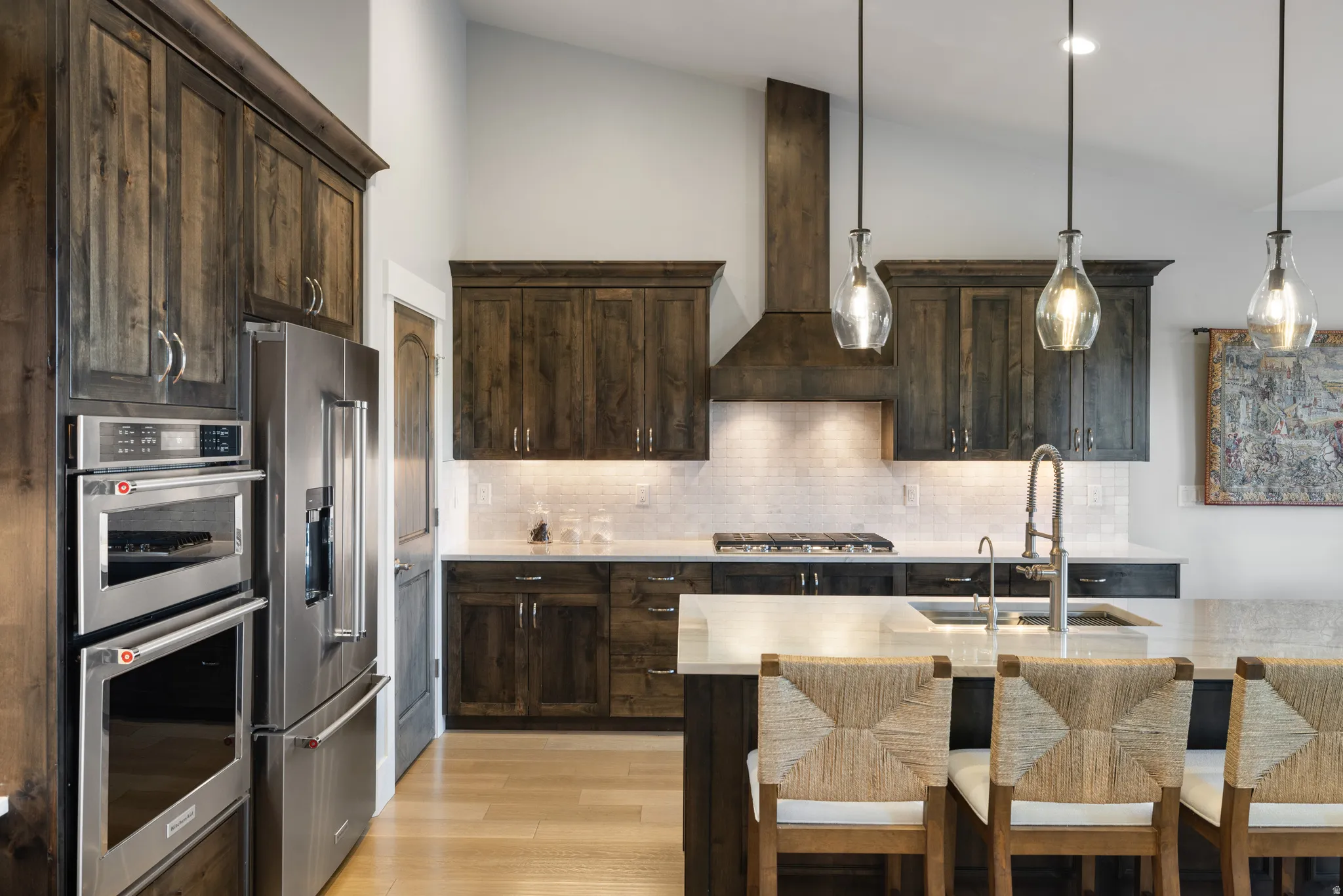 Kitchen featuring dark wood-finish cabinetry, stainless steel double ovens, and a matching refrigerator
